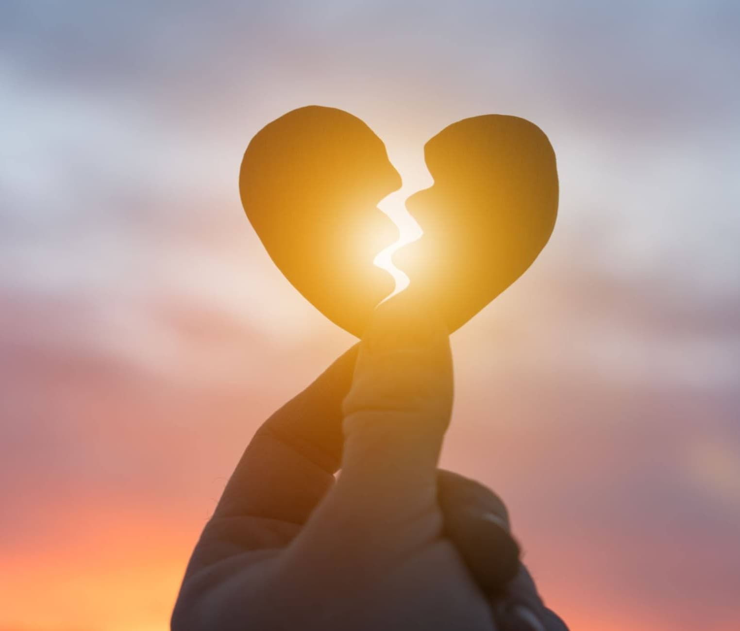 The silhouette of a hand holding a broken heart